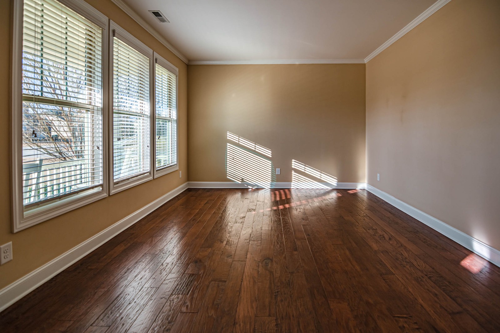 Bright, sunlit living room with warm site-finished hardwood flooring